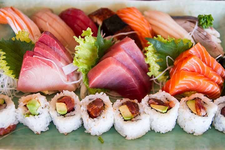 Platter of yellowtail, tuna and salmon sashimi with maki rolls