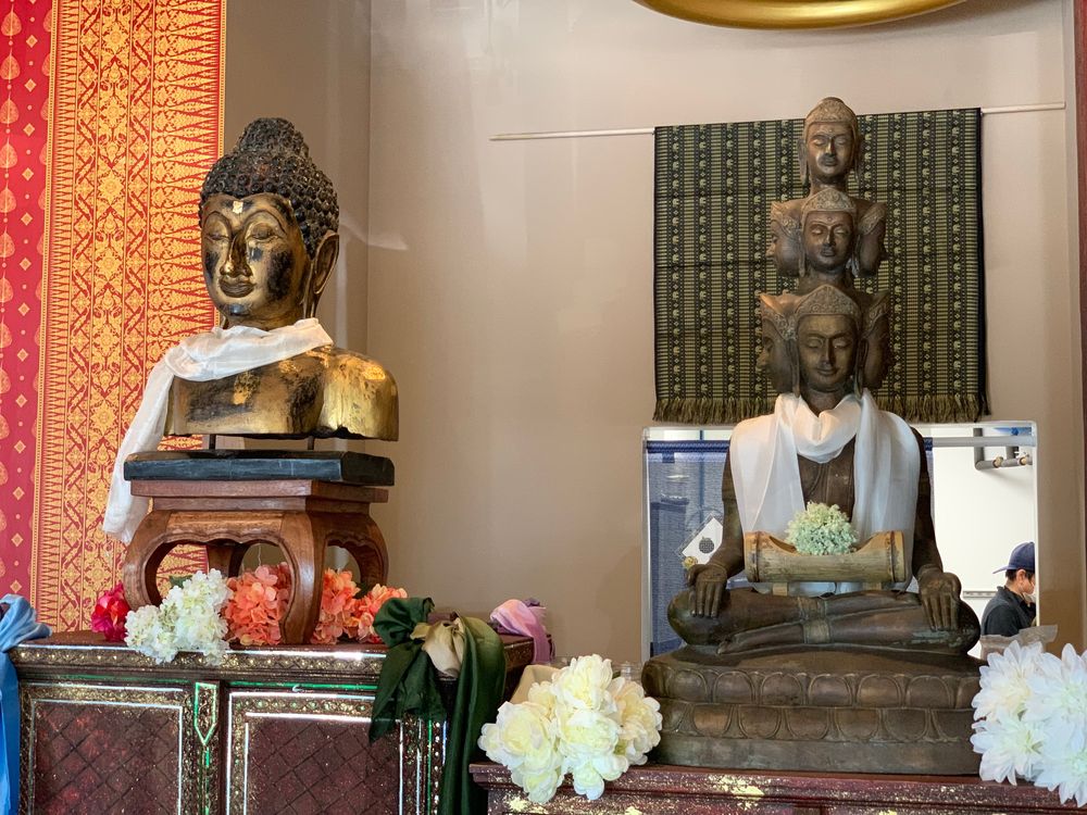 Two Buddha statues with flowers among the restaurant décor