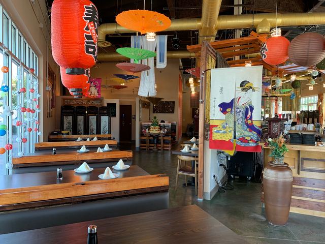 Dining room with long wooden tables beneath orange paper lanterns and parasols