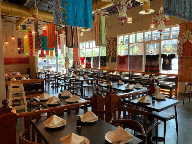 Dining room set with folded napkins under hanging Thai textiles