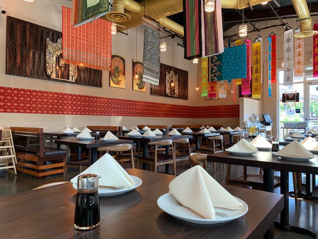 Dining room with folded napkins and colorful textiles hanging overhead
